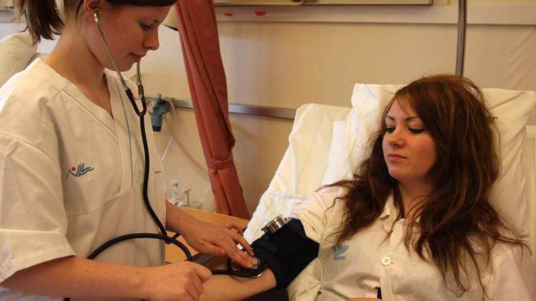 Sjuksköterska tar blodtryck på kvinnlig patient
