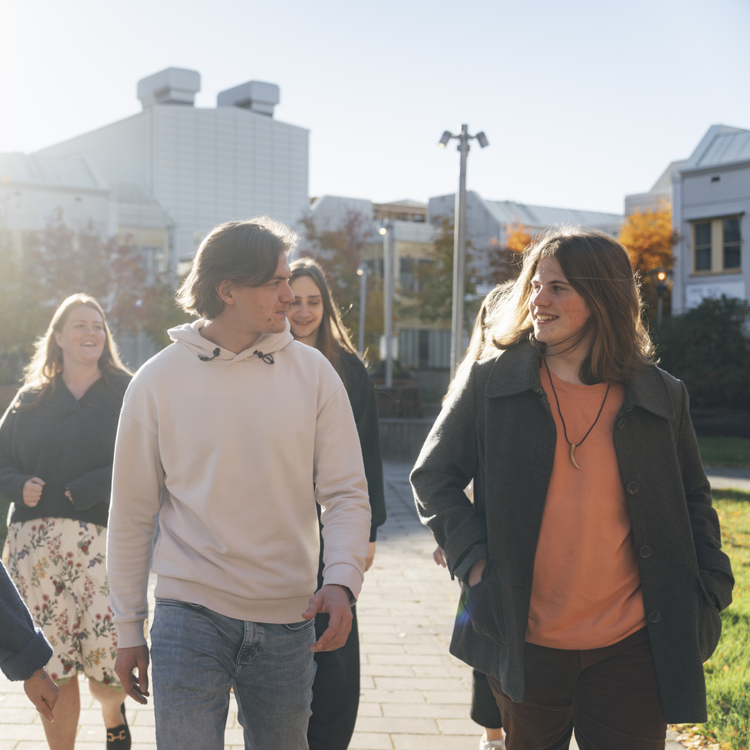 En grupp människor som går tillsammans genom campus utomhusmiljöer.