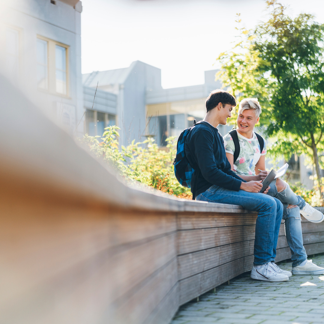 A couple of people sitting on top of a wooden bench.