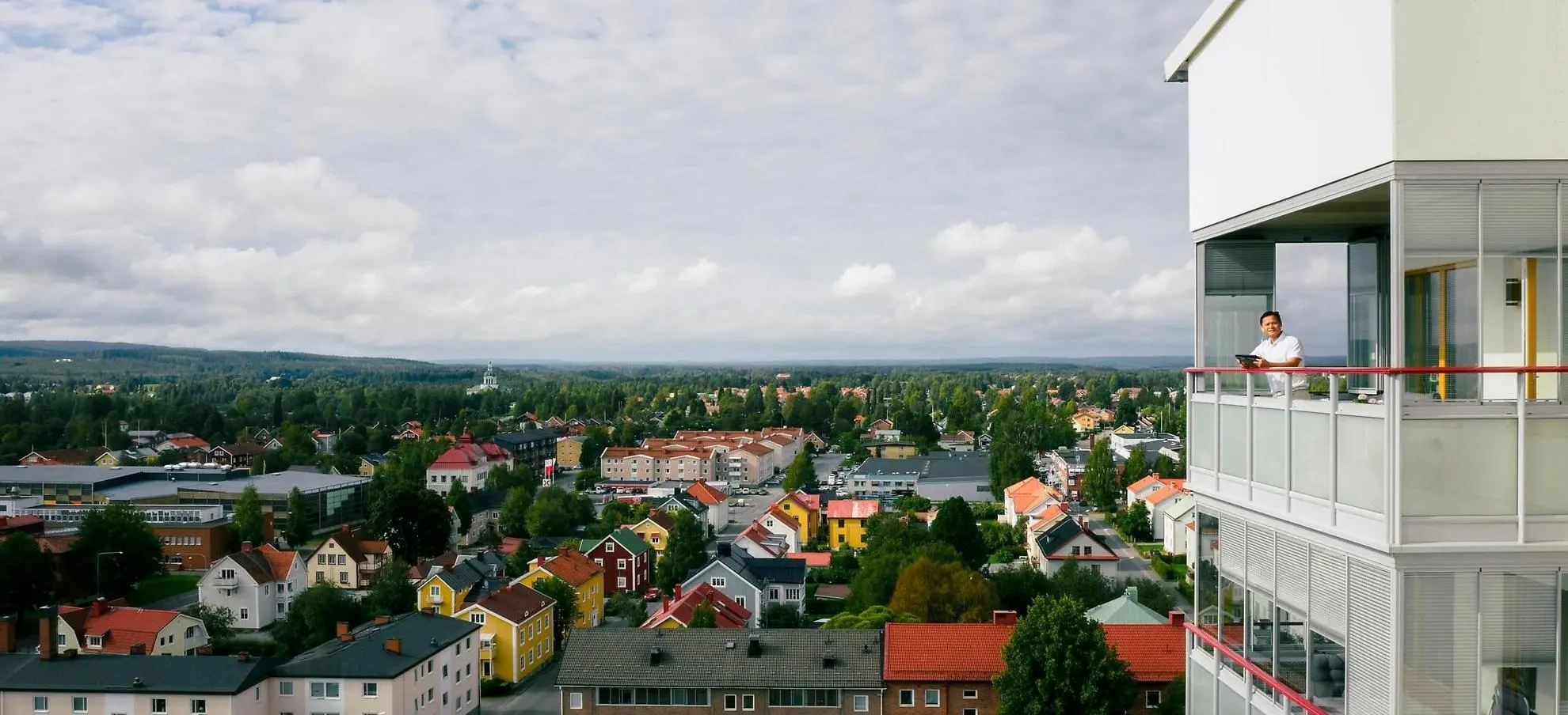 Kvinna står på en inglasad balkong i ett höghus