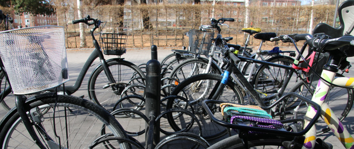 Flera cyklar som står på rad i ett cykelställ. 