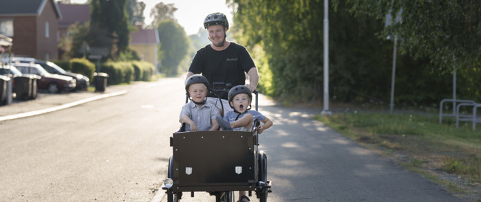 En man som skjuter en vagn med två barn i.
