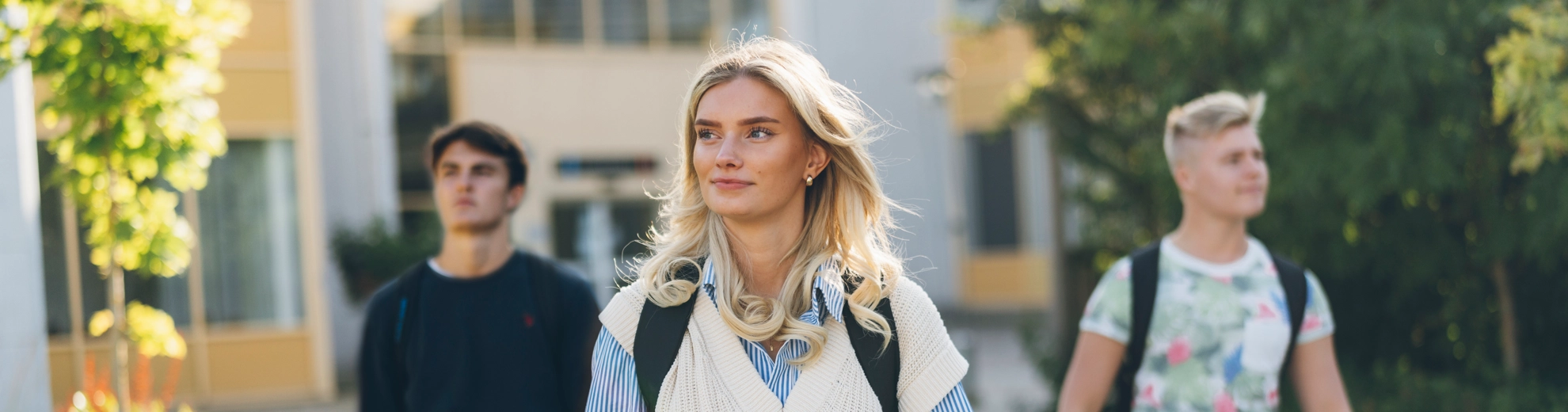 En grupp människor som går genom campusområdets utomhusmiljö.