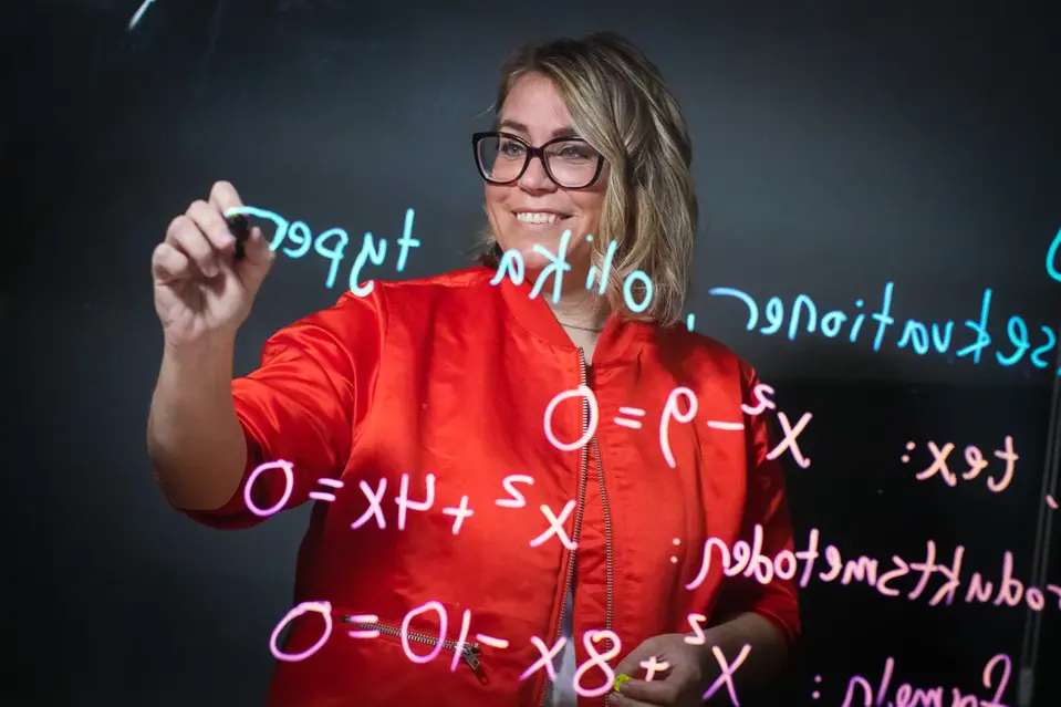 Sofia som skriver matematiska formler på en glastavla. Fotograf Patrick Degerman