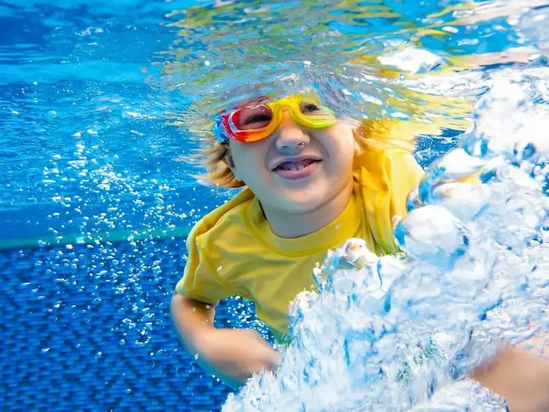 Barn som tittar med sina simglasögon under vattnet