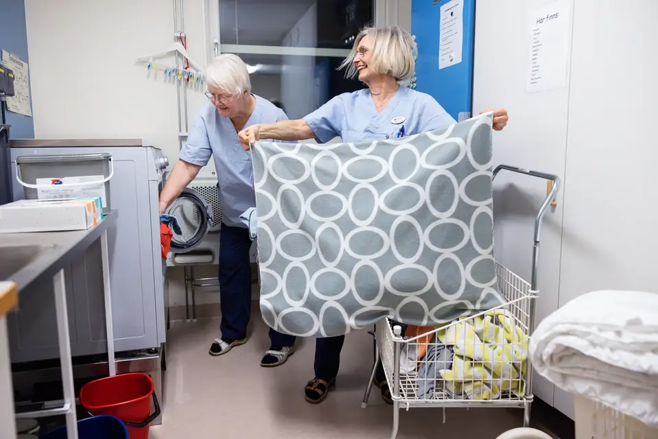 Glada seniorer arbetar i tvätten på ett vård- och omsorgsboende.