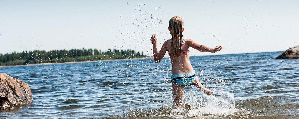 En flicka som springer eller hoppar i vattnet vid Bovikens havsbad