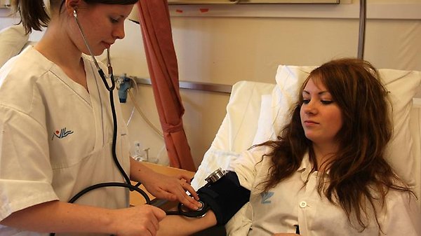 Sjuksköterska tar blodtryck på kvinnlig patient